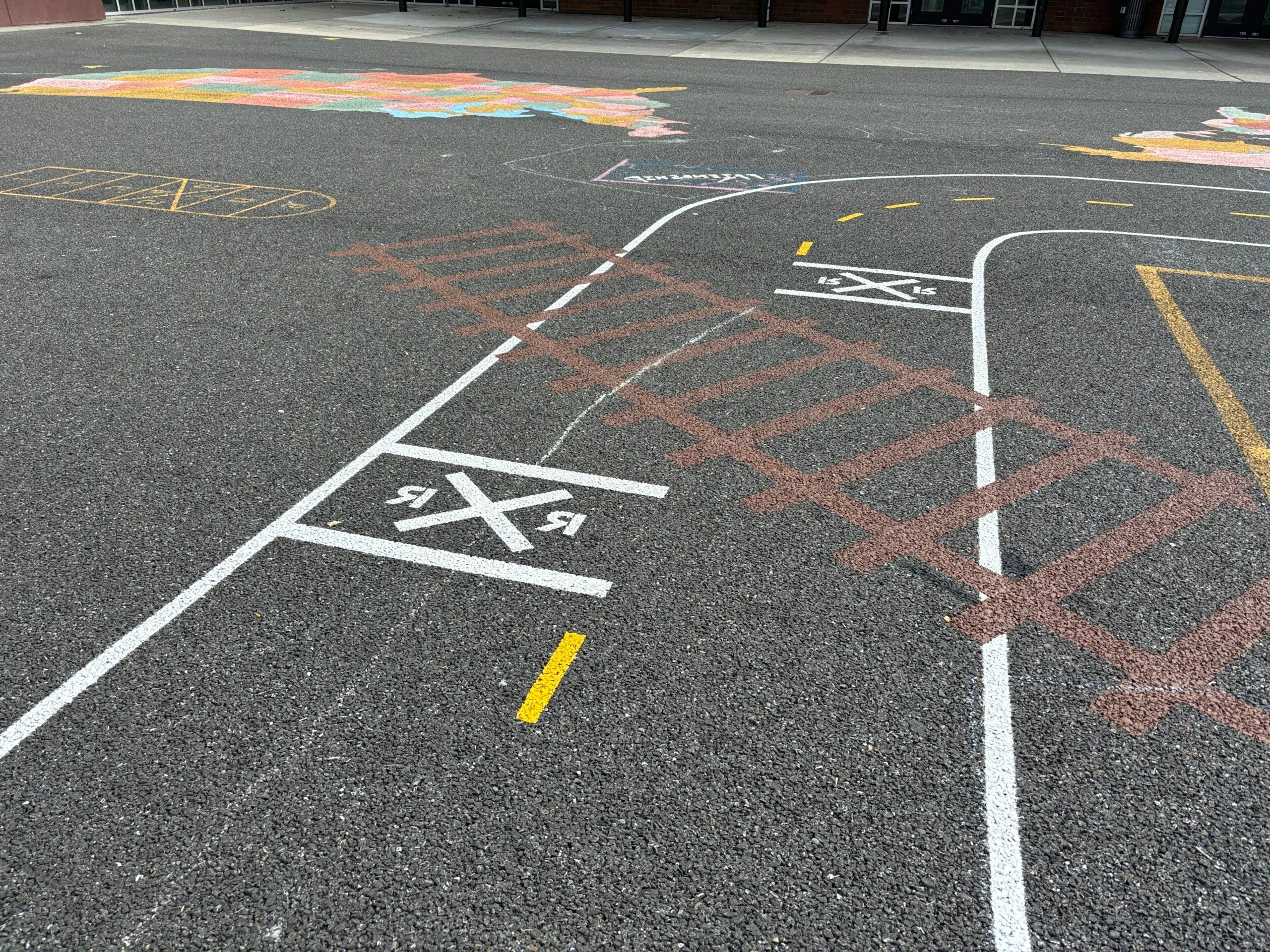 Miniature road painted on blacktop with painted railroad tracks.